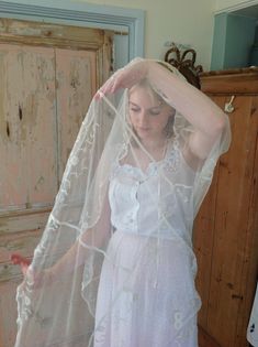 a woman in a white dress is wearing a veil and holding her head with both hands