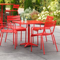 an outdoor table with red chairs around it