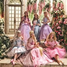 there are many princesses sitting on the steps in front of some flowers and trees