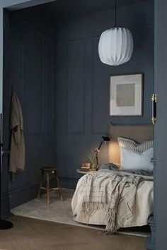 a bedroom with dark blue walls and white lamps hanging from the ceiling, along with a bed