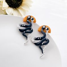 These stylish white and black snake earrings are the perfect edgy accessory for bold fashion lovers. Made from lightweight polymer clay, these unique earrings not only look great but also feel comfortable to wear thanks to their hypoallergenic surgical steel posts, making them ideal for those with sensitive ears. With a clip-on option available for those who do not have pierced ears, they make a trendy gift for her that's perfect for any occasion. Whether you're searching for Christmas gifts or thoughtful birthday gifts, these small batch, artisan-made statement earrings make a unique addition to any jewelry collection. Treat someone special or indulge yourself with these captivating earrings! Since all items are handmade you may see slight variations in color or pattern from the pictures. Clay Christmas Gifts, White And Black Snake, Earrings Edgy, Edgy Earrings, Edgy Accessories, Clay Christmas, Gifts For Girlfriend, White Snake, Earrings Clay