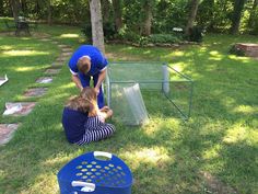 two children are playing in the yard with an animal cage and other items on the grass