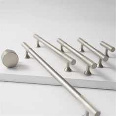 several stainless steel handles and knobs on a white surface