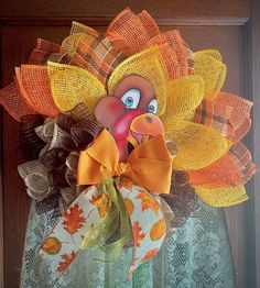 a wreath made to look like a turkey with an orange head and yellow leaves on it