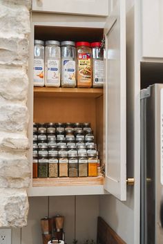 an open cabinet in a kitchen filled with spices