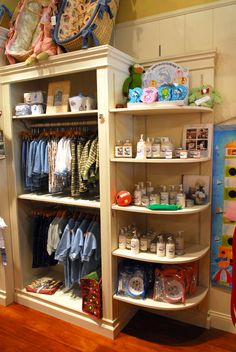 a closet filled with lots of baby clothes and toys on shelves next to a wall