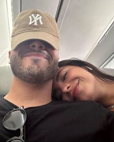 a man and woman are smiling while sitting on an airplane together with their arms around each other