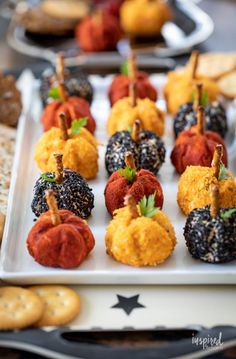 small pumpkins and gourds are arranged on a white platter with crackers