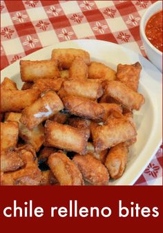 a white plate topped with tater tots next to a bowl of tomato sauce