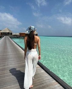 a woman standing on a pier looking out at the ocean