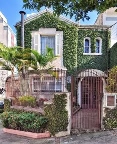 an old house covered in vines and ivys with a gate leading to the entrance