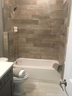 a white toilet sitting next to a bath tub in a bathroom under a light fixture