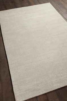 a large white rug on top of a wooden floor