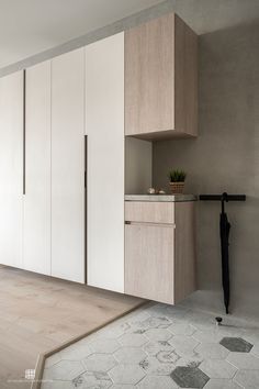 an empty room with white cupboards and wood flooring on the walls, in front of a black umbrella