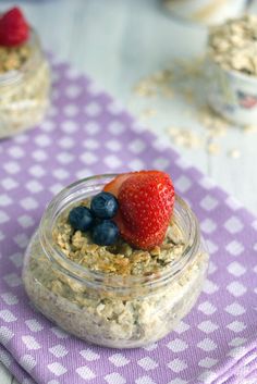 a bowl of oatmeal with strawberries and blueberries in it on a table