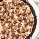 a pie with chocolate and peanut butter toppings is shown on a white platter