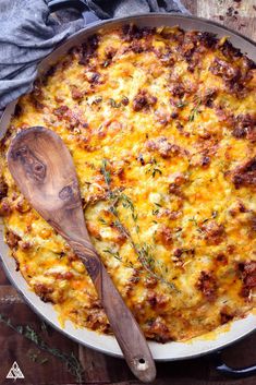 a casserole with meat and cheese in a pan next to a wooden spoon