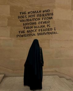 a woman standing in front of a wall with writing on it that reads, the woman who does not require vallation from anyone else