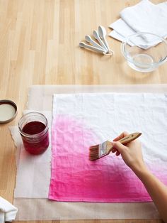 a person is painting on a piece of paper with paintbrushes and some other items