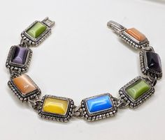 Gorgeous vintage signed Premier Designs bracelet. Silver-tone links with textured edges. Each one has a brightly colored rectangle moonglow cabochon inset into it. Locking foldover clasp. Measures 7 inches long and 1/2 inch wide. Excellent condition. Shop Policies: Shipping: All items will be shipped through the USPS unless otherwise marked. Most items will be shipped first class. Expect shipment within 1-2 business days from date of payment. Refunds:Vintage items are all used and have varying a Retro Multicolor Metal Bracelets, Vintage Rectangular Cabochon Jewelry, Vintage Multicolor Cabochon Bracelets, Antique Dollhouse, Premier Designs, Vintage Bracelet, Moon Glow, Red Rhinestone, Design Silver