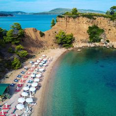 an aerial view of a beach with umbrellas and chairs on the sand next to water