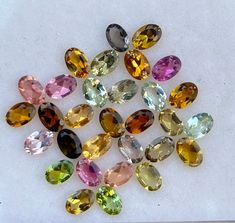 many different colored gems are arranged in a circle on a white surface, with one being surrounded by smaller ones