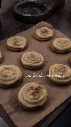 cookies with white frosting and cinnamon sprinkles are on a baking sheet