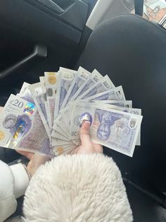 a person holding money in their hand while sitting in the back seat of a car