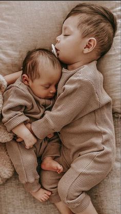 two babies are sleeping together on a couch