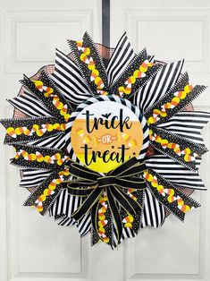 a trick or treat wreath hanging on the front door with black and white striped ribbon