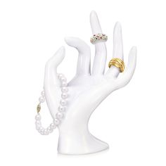 a hand with two rings on it and pearls around the middle of its fingers, in front of a white background