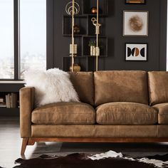 a living room with a brown couch and white pillows on top of it's back