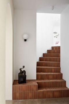 a set of stairs leading up to a white wall with a sculpture on the bottom