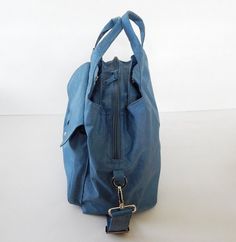 a blue purse with a keychain hanging from it's front pocket on a white surface