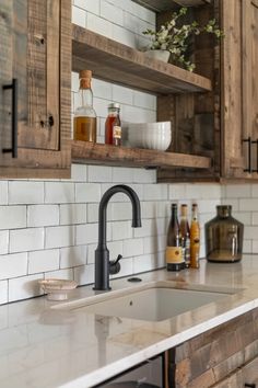 a kitchen with wooden cabinets and marble counter tops, white subway backsplash and black faucet