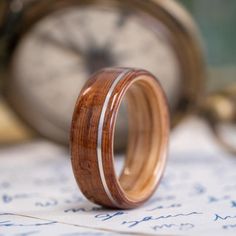 a wooden ring sitting on top of an open note with a clock in the background