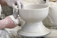 a person is making a bowl out of clay