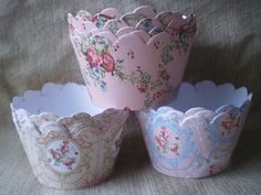 three paper cupcake cases with floral designs on the top and bottom, one is pink