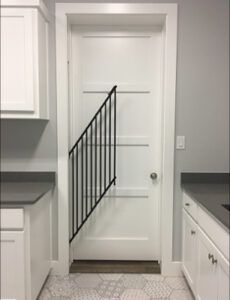 a white door with a black railing in the middle of a kitchen area next to cabinets