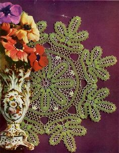 an old crocheted doily pattern with flowers and vases on the side