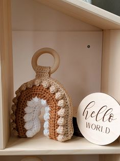 a crocheted gingerbread house sits on a shelf next to a hello world sign