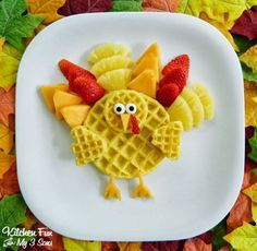 a white plate topped with waffles covered in fruit and a turkey shaped cookie