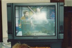 two people watching television in front of a fish tank