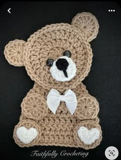 a crocheted teddy bear with a white bow