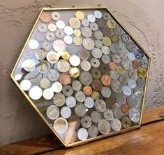 a wooden table topped with lots of different types of coins in a hexagonal frame