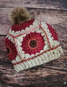 a red and white crocheted hat with a pom - pom on top