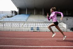 a woman running on a track in front of an empty bleachers