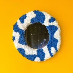 a blue and white circular object on a yellow wall with a mirror in the center