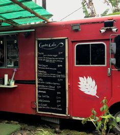 the food truck is red with white writing on it's side and green awning