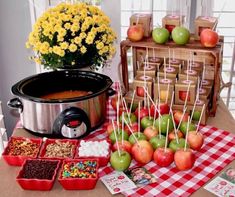 an assortment of apples and candies on a table next to a crock pot